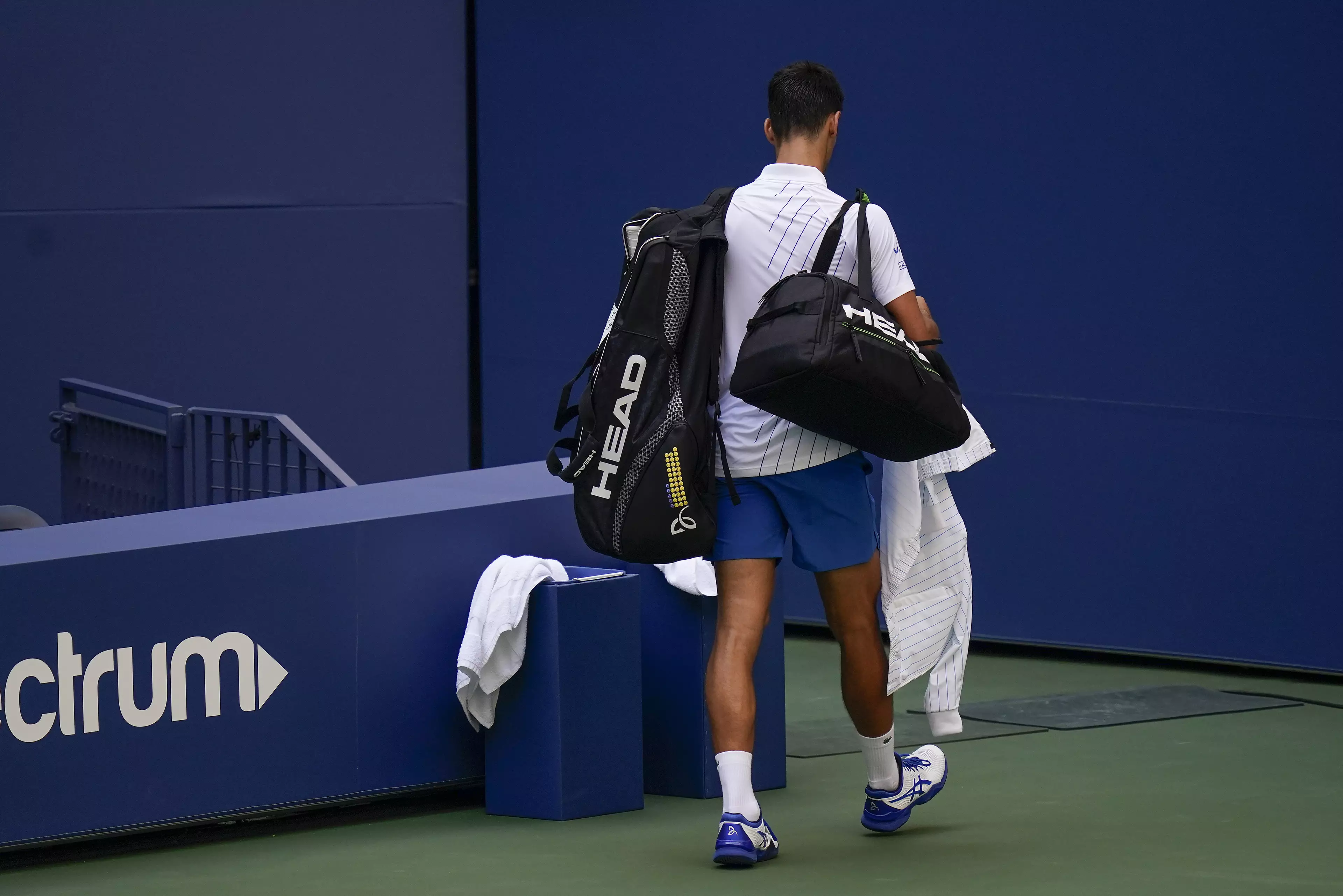 Novak Djokovic leaves the court after sensationally defaulting the match.