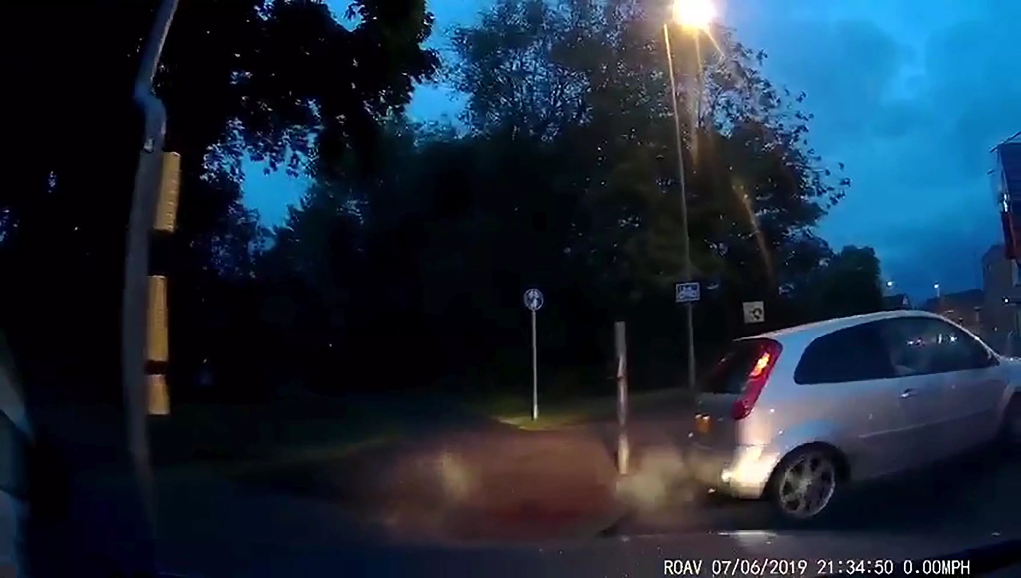 The car clips the kerb and crashes into a post.