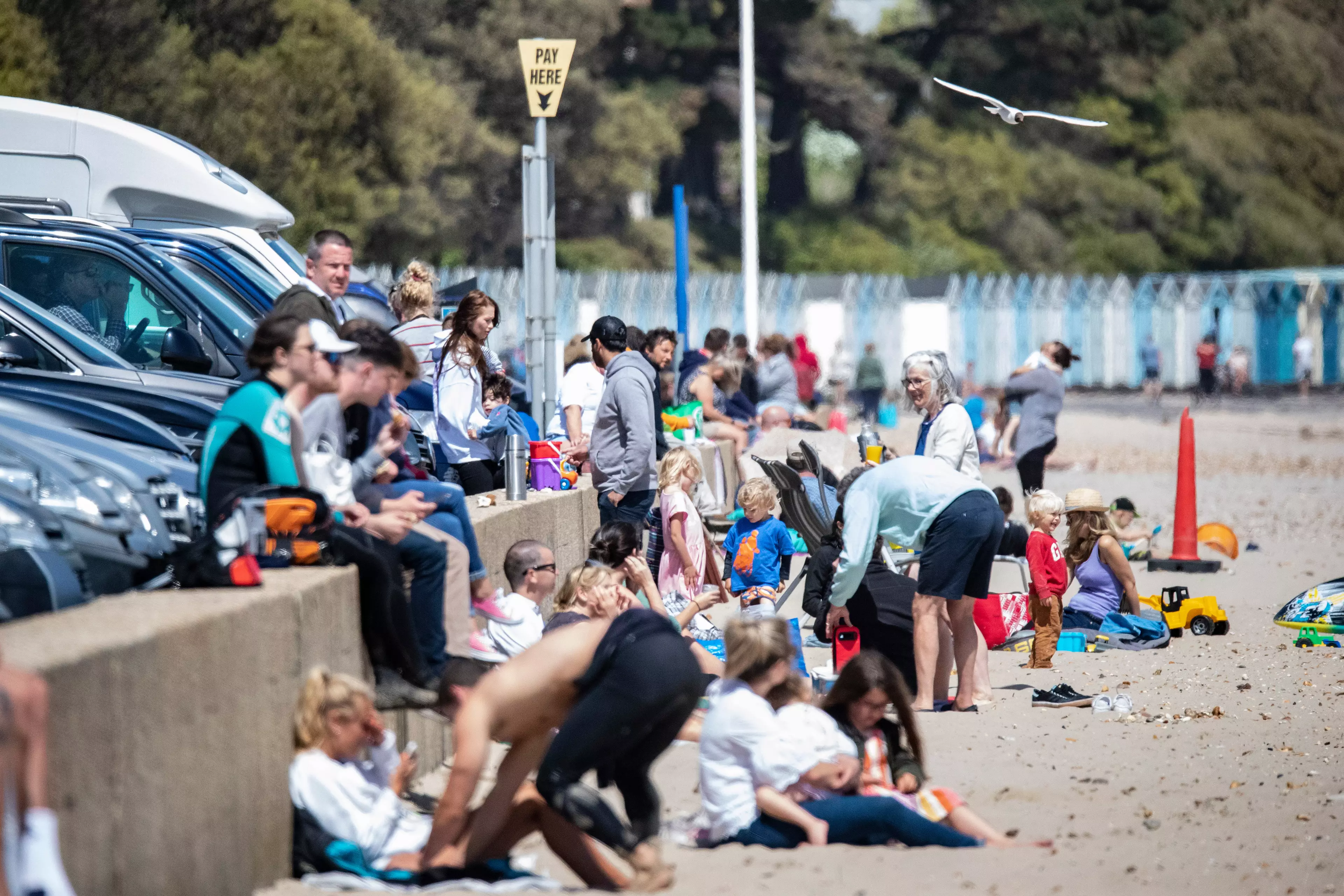 Crowds of people gathered on a sunny Bournemouth beach.