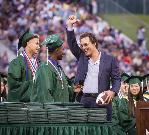 Kamden Perry, left, and Jephaniah Lister present actor Matthew McConaughey with an autographed football at the school's graduation ceremony.