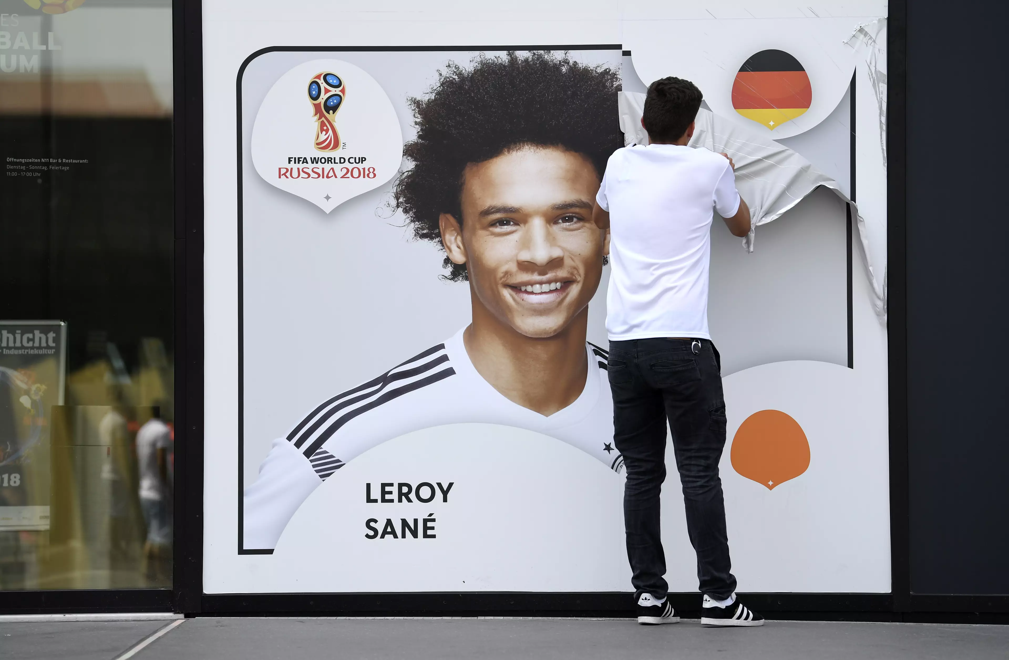A worker peeling a picture of Leroy Sane off the wall of the German football museum. Image: PA