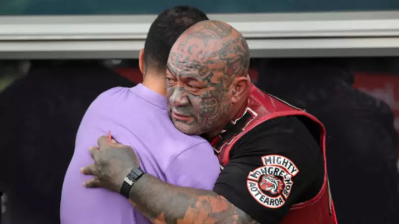 A gang member consoles mourners.