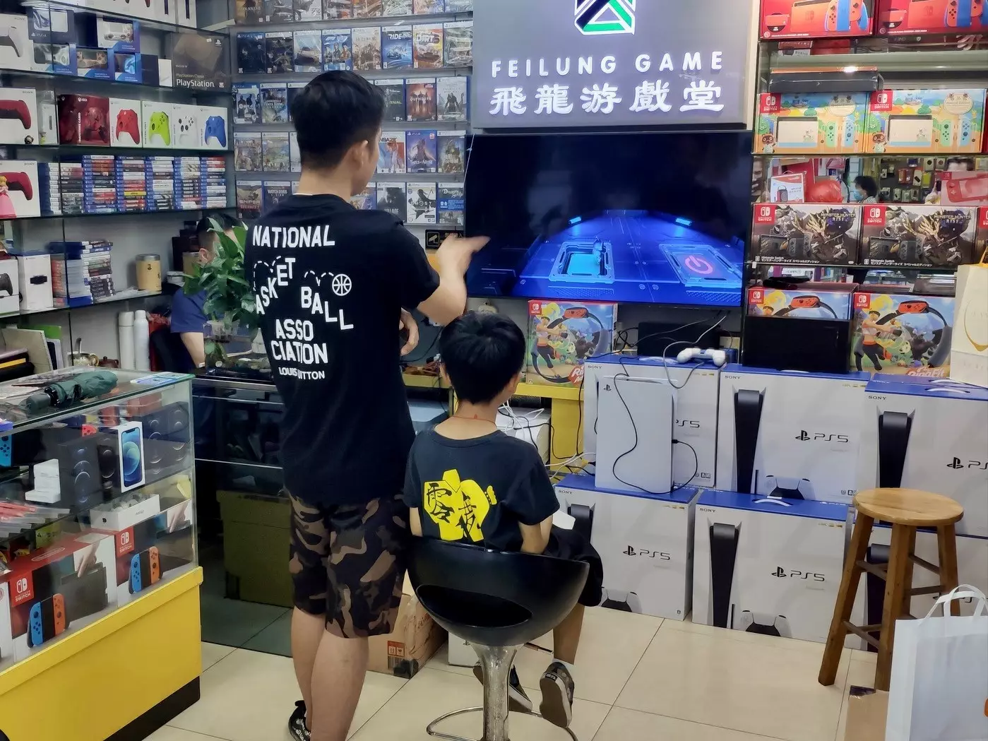 Customers in a store in the electronics shopping area of Huanqiangbei in Shenzhen, with a stack of PS5s clearly visible /