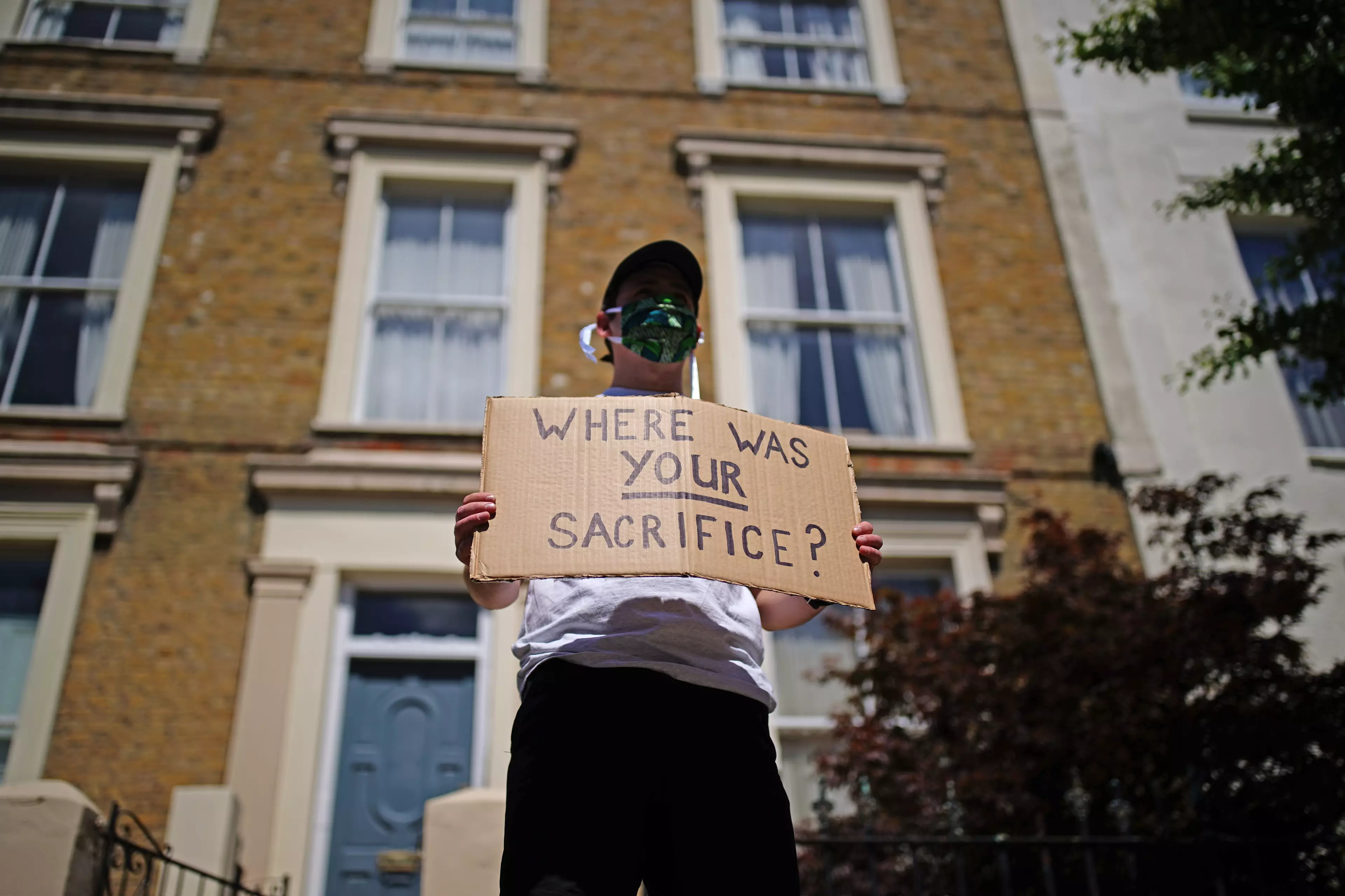 A protester with a sign outside Dominic Cummings' house.