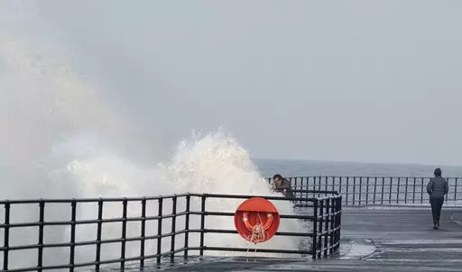 A man trying to take a selfie as the wave splashes him.