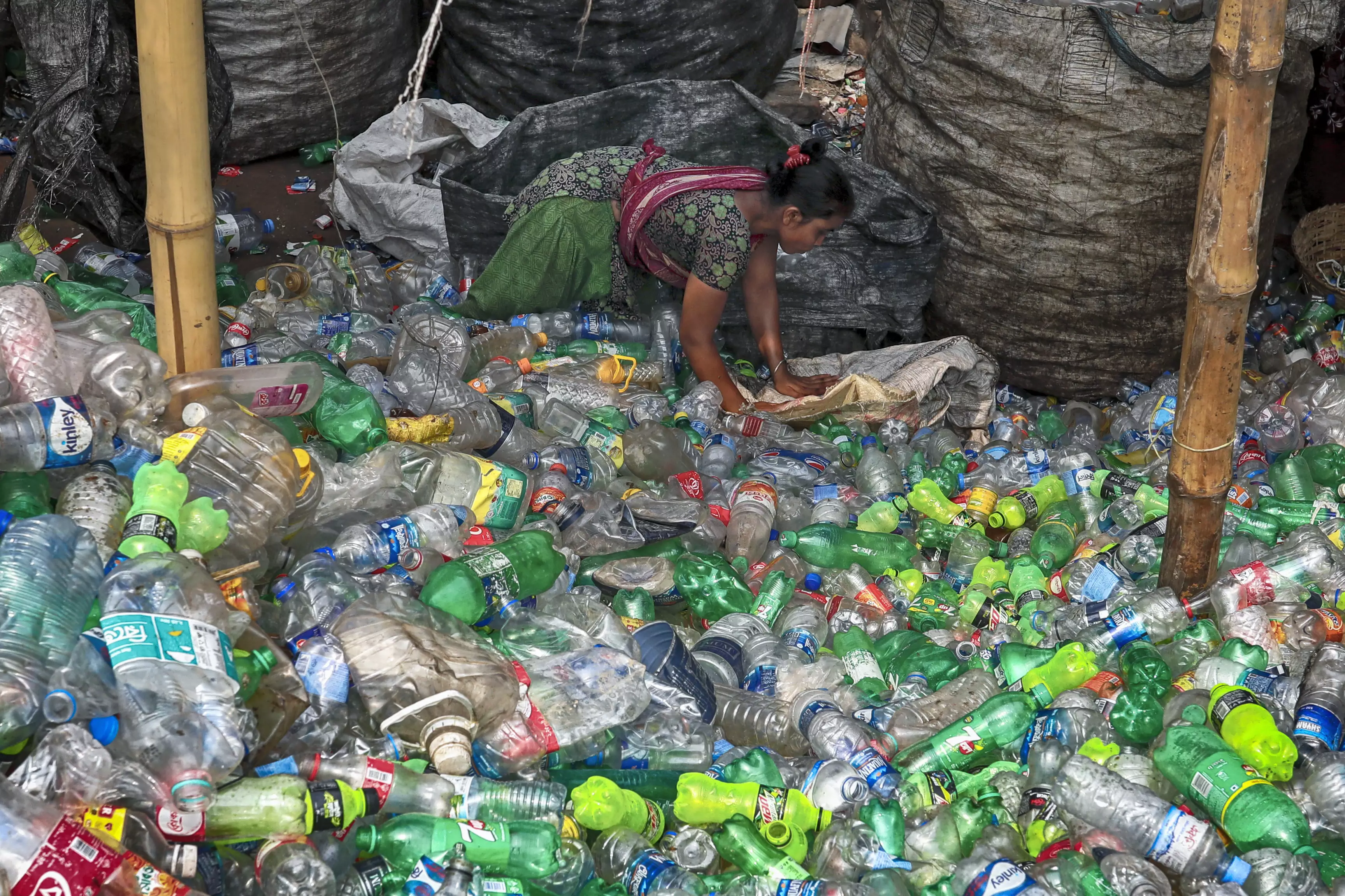 Worker trying to sort the plastic at a recycling plant.