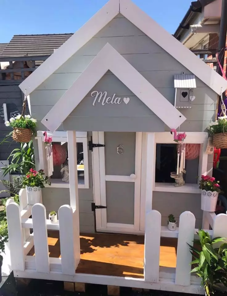 The beautiful house features a white picket fence and hanging baskets around the porch (