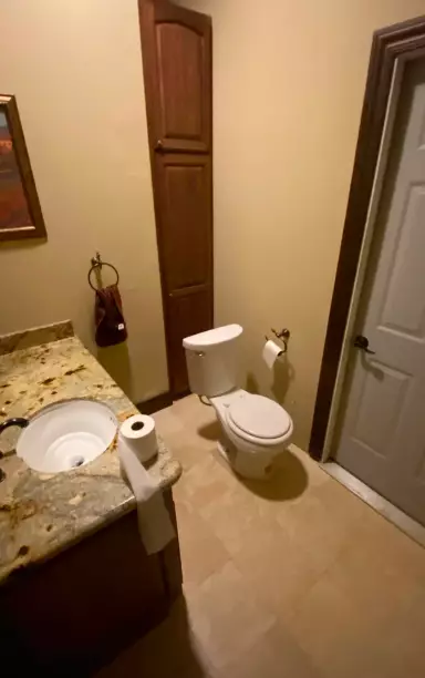 The toilet can be seen in front of the cupboard (