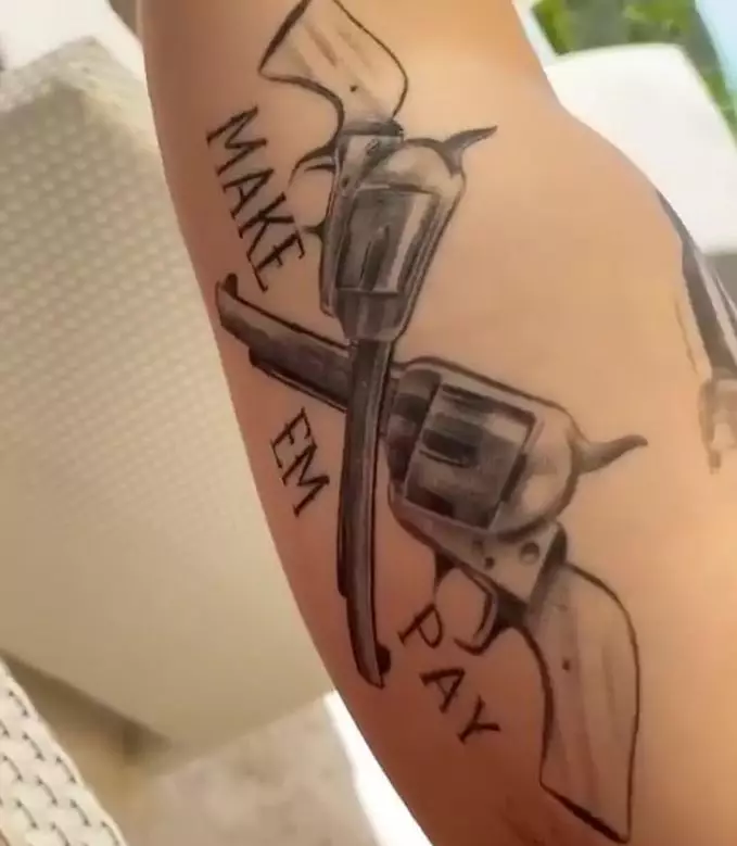The bicep tattoo with the words 'MAKE 'EM PAY'.