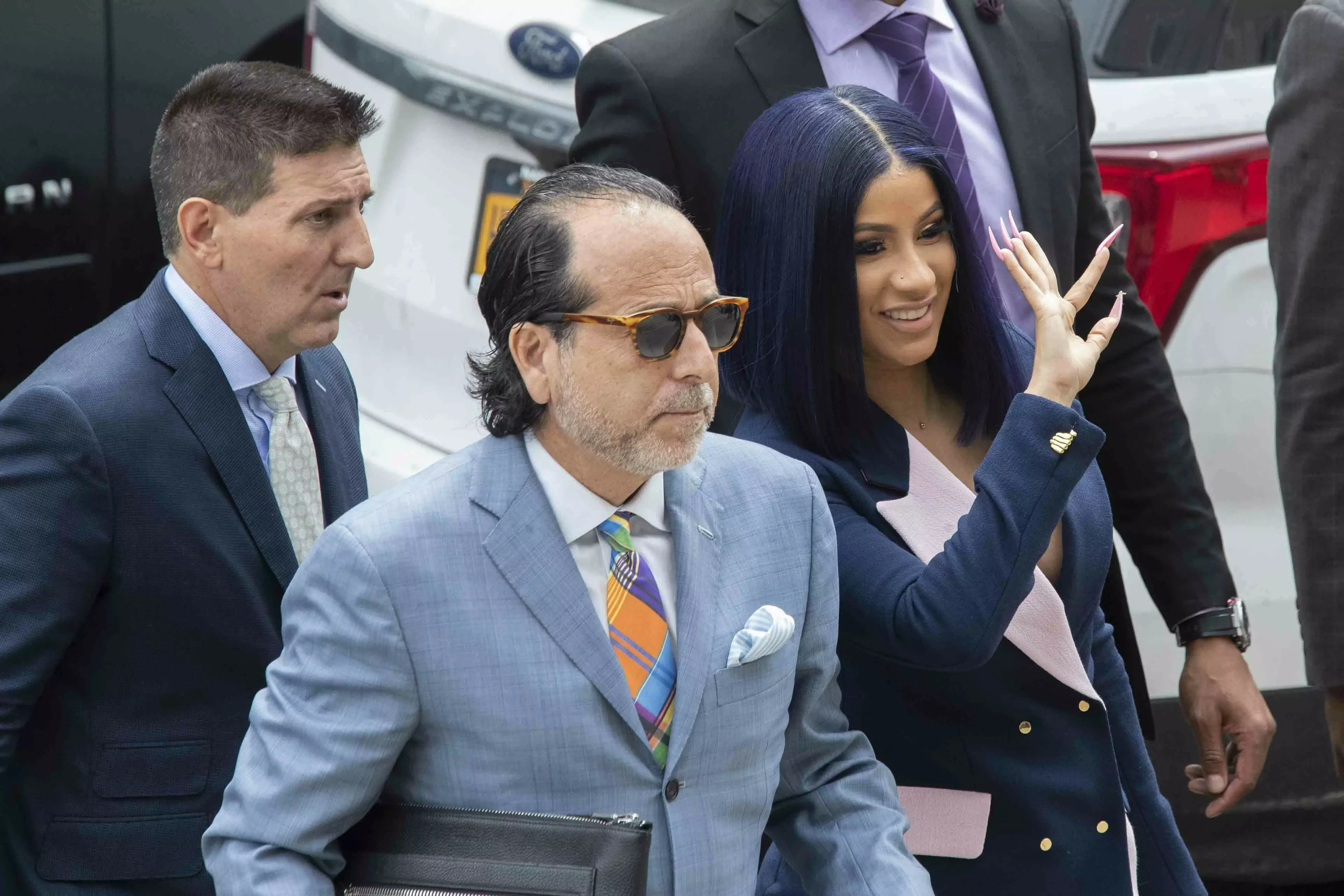Cardi B waves at fans as she arrives for a hearing at Queens County Criminal Court