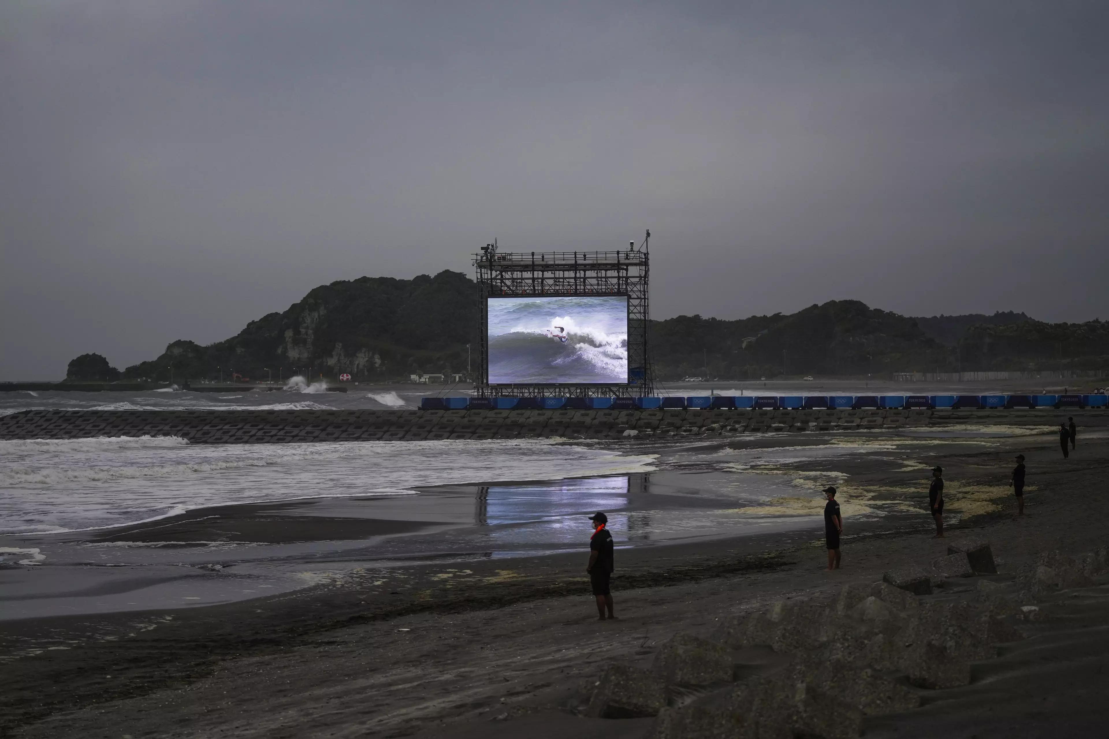 A giant screen displays the third round of men's surfing competition at the 2020 Summer Olympics, Monday, July 26, 2021, at Tsurigasaki beach in Ichinomiya, Japan. (