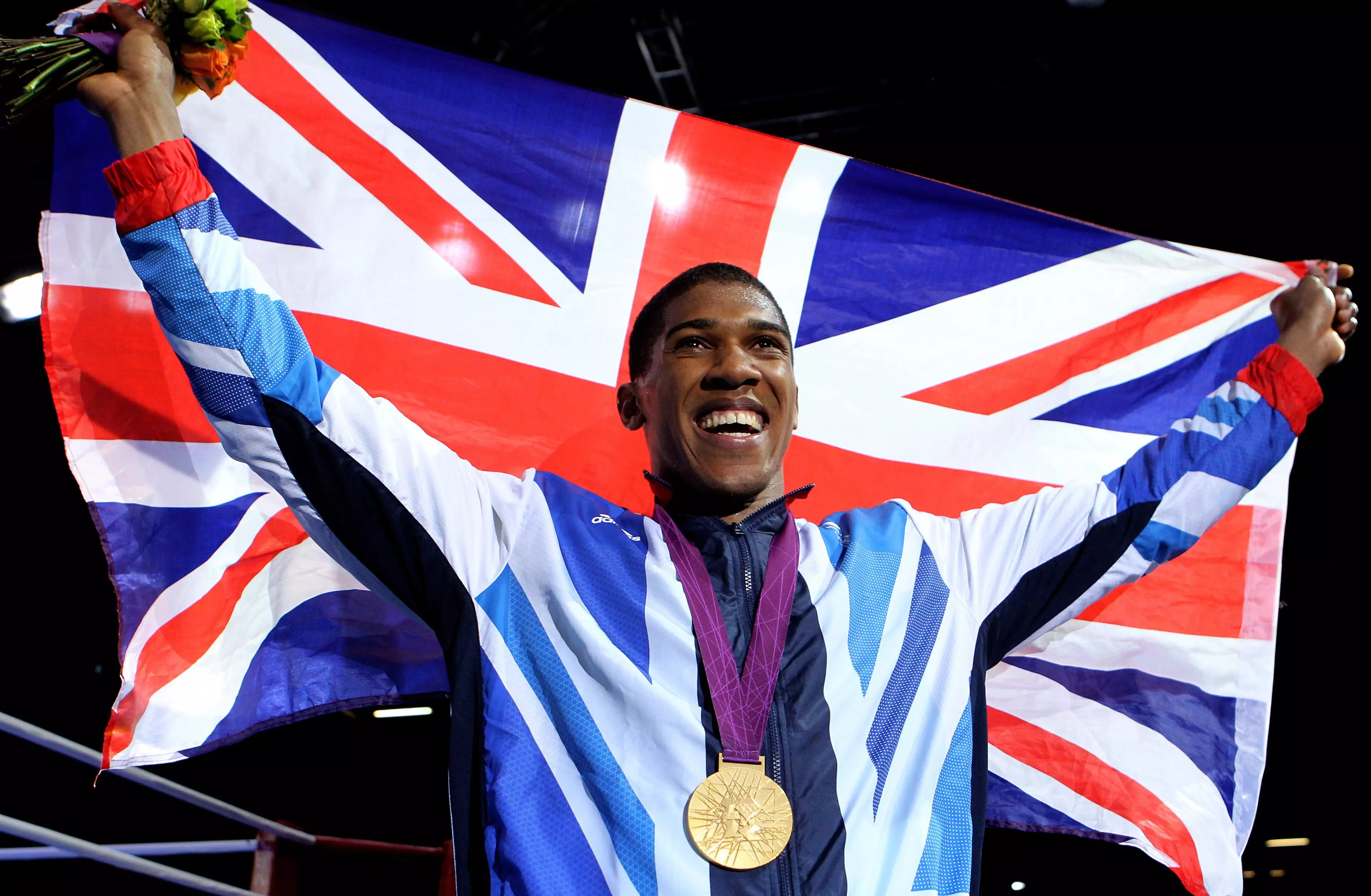Joshua raises the Union Jack flag with the gold medal around his neck. Image: PA