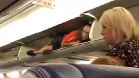 Passengers Left Baffled After Flight Attendant Climbs Into Overhead Lockers