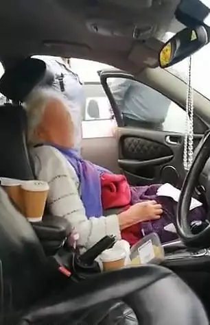 The elderly lady can be seen sitting in the front seat of the family's car (