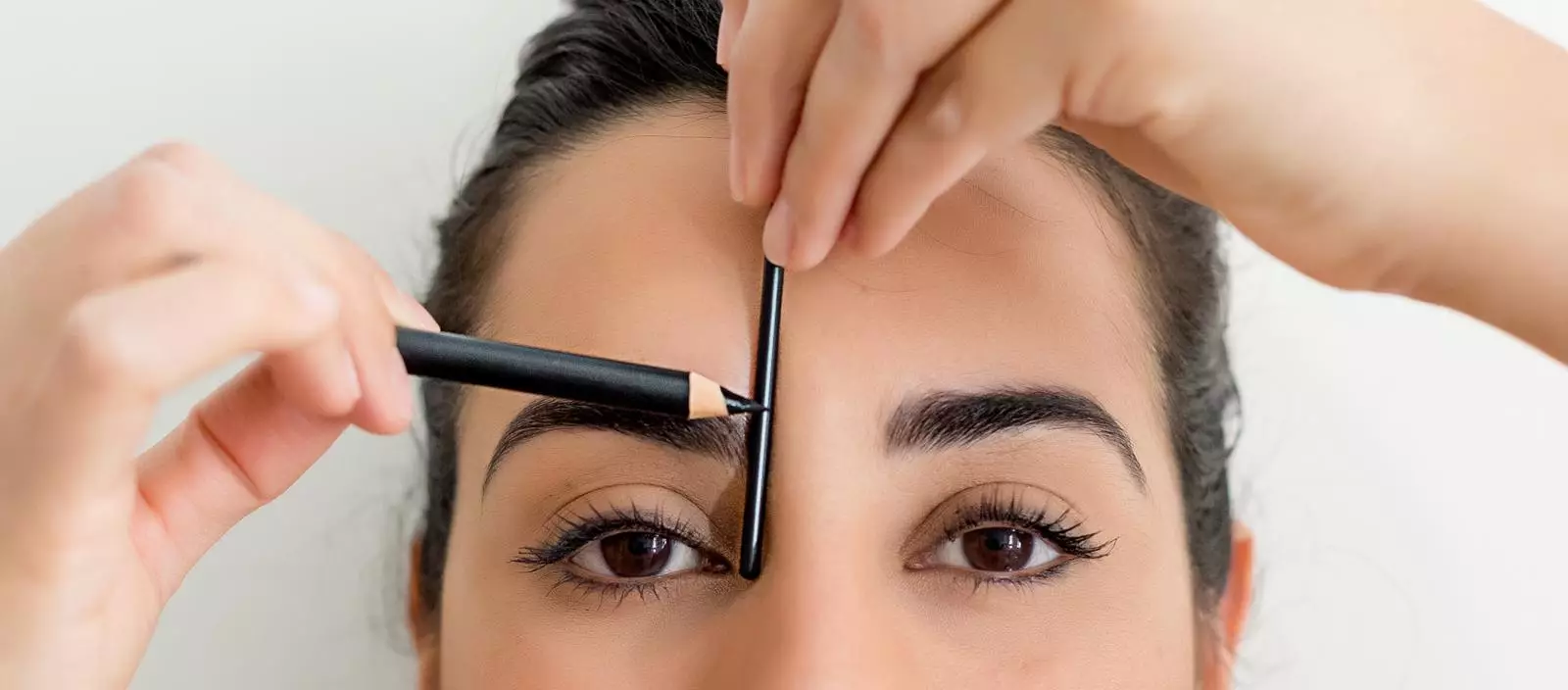Use a sharp pencil and ruler to align the inner edges of your brows with the bridge of your nose to map out your desired shape (