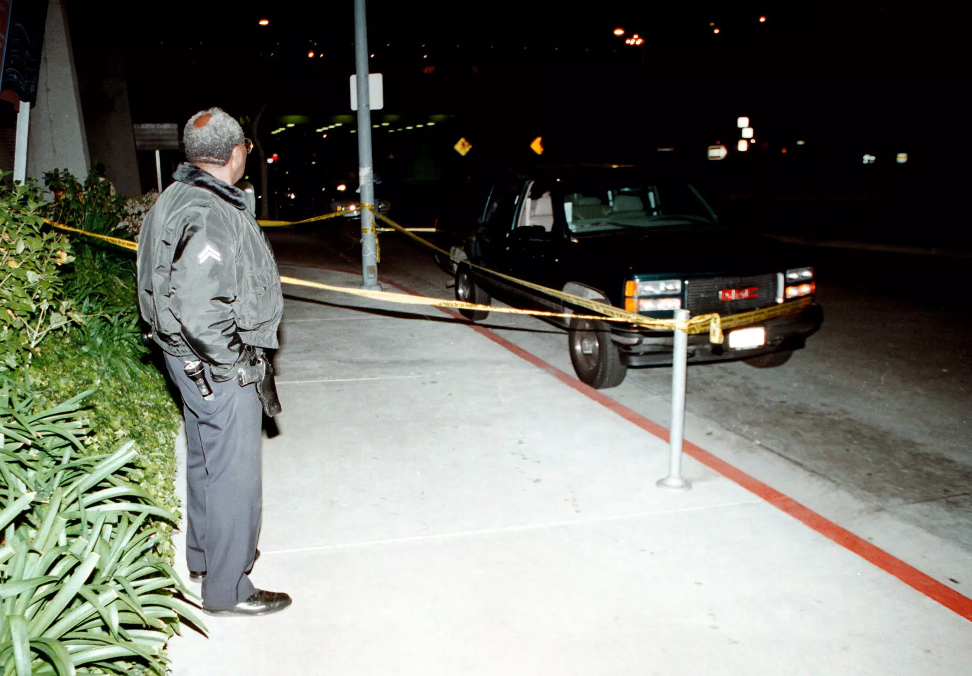 An LAPD officer watches over the GMC Suburban, which Wallace was inside when he was shot.