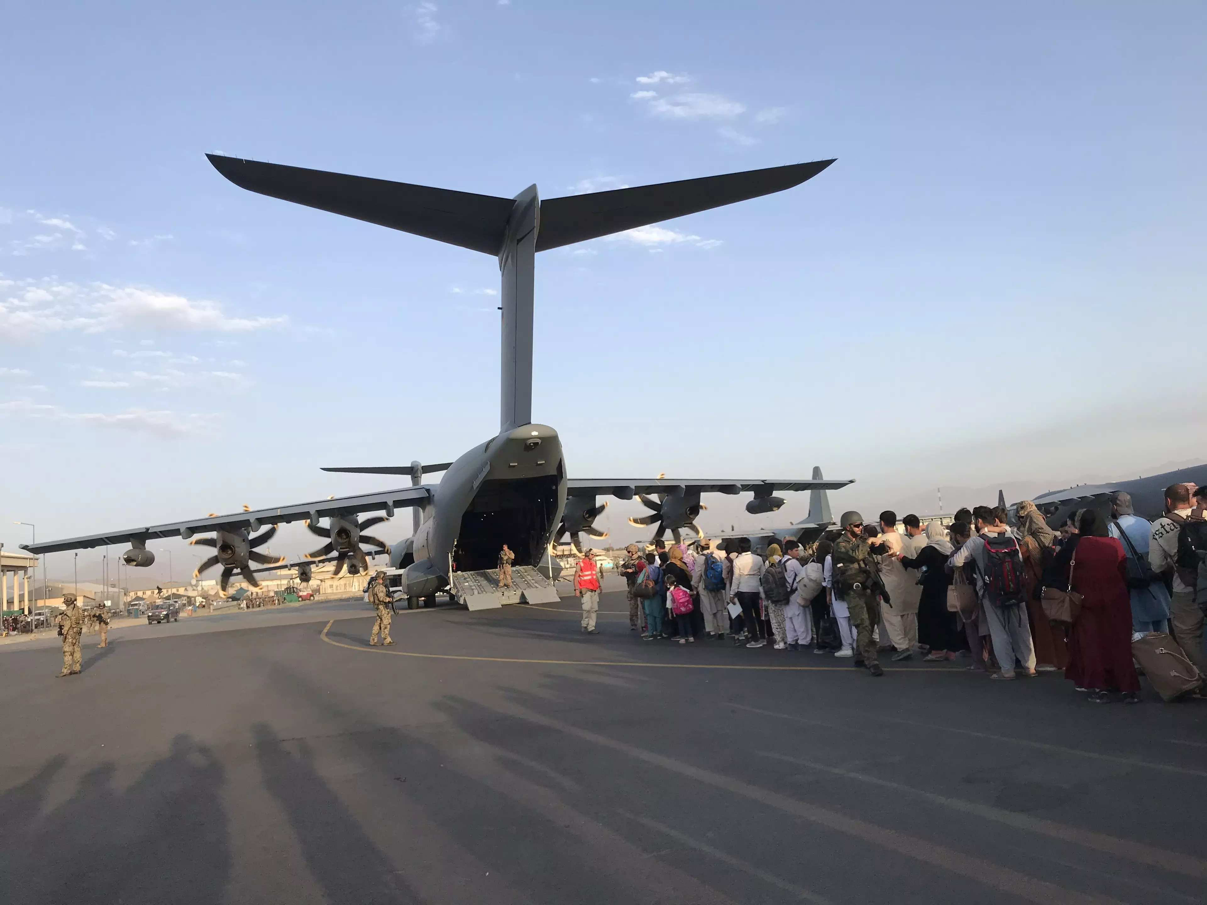 People queue up to board a German military aircraft at Kabul airport.