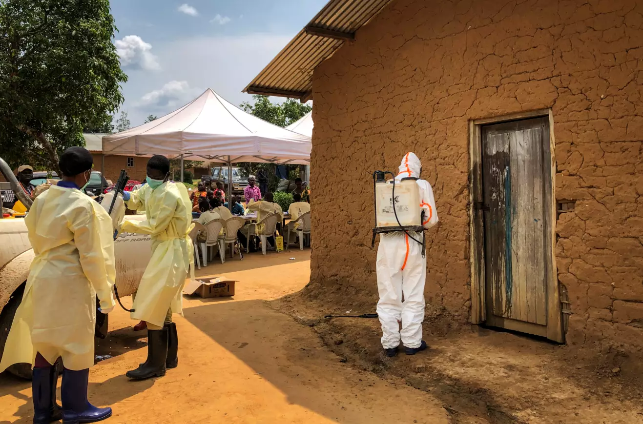A worker from the World Health Organization (WHO) decontaminates the doorway of a house on a plot where two cases of Ebola were found, in the village of Mabalako.