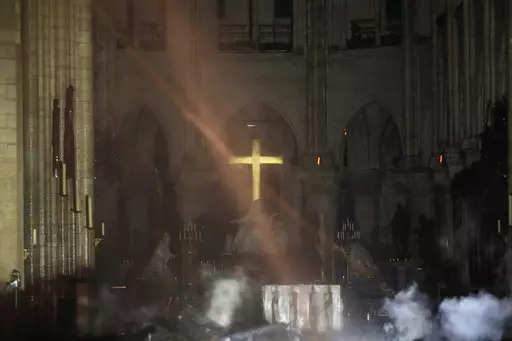 The cross can be seen through the smoke inside the Notre Dame Cathedral.