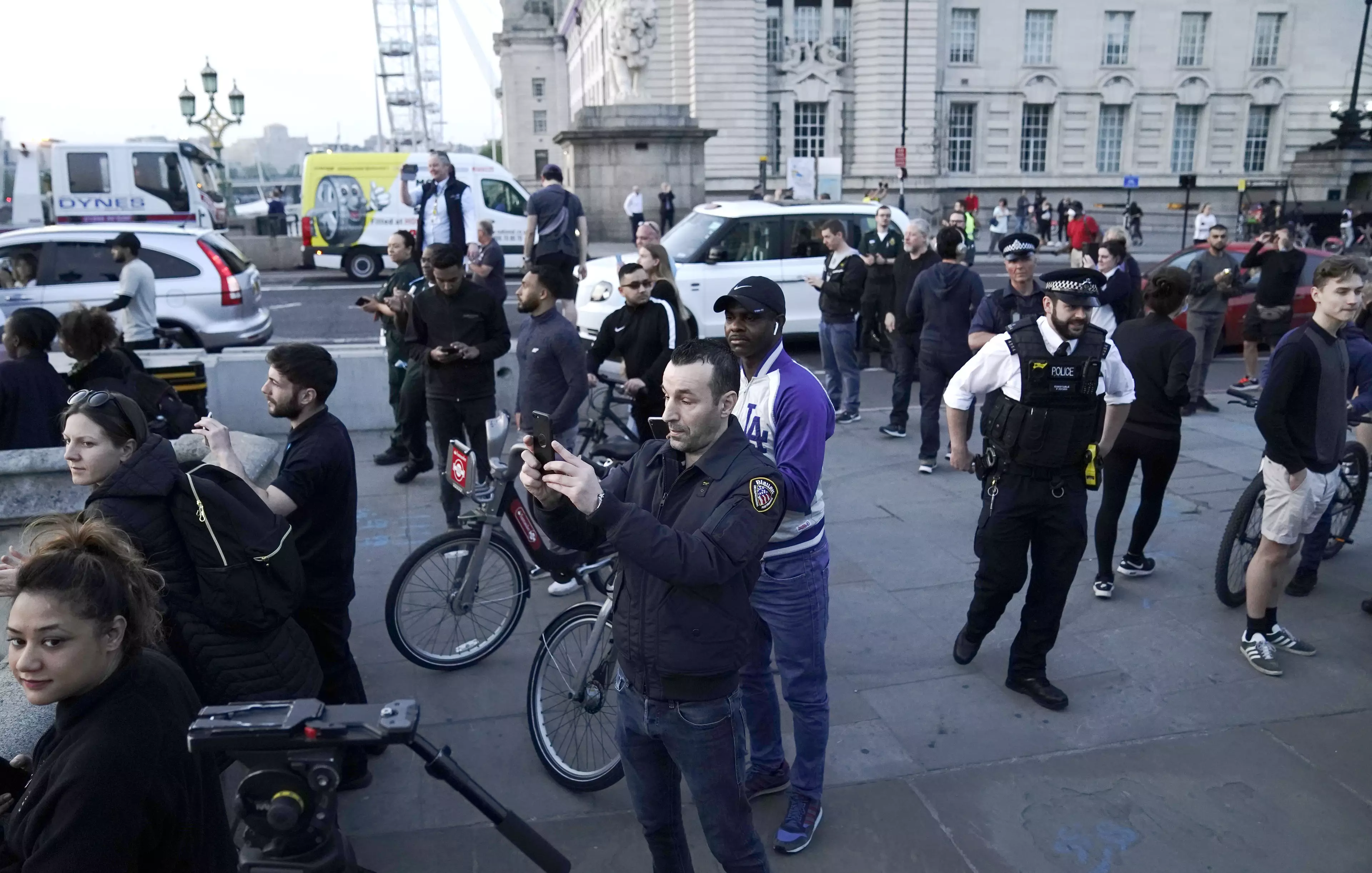 People and emergency responders stand on Westminster Bridge.