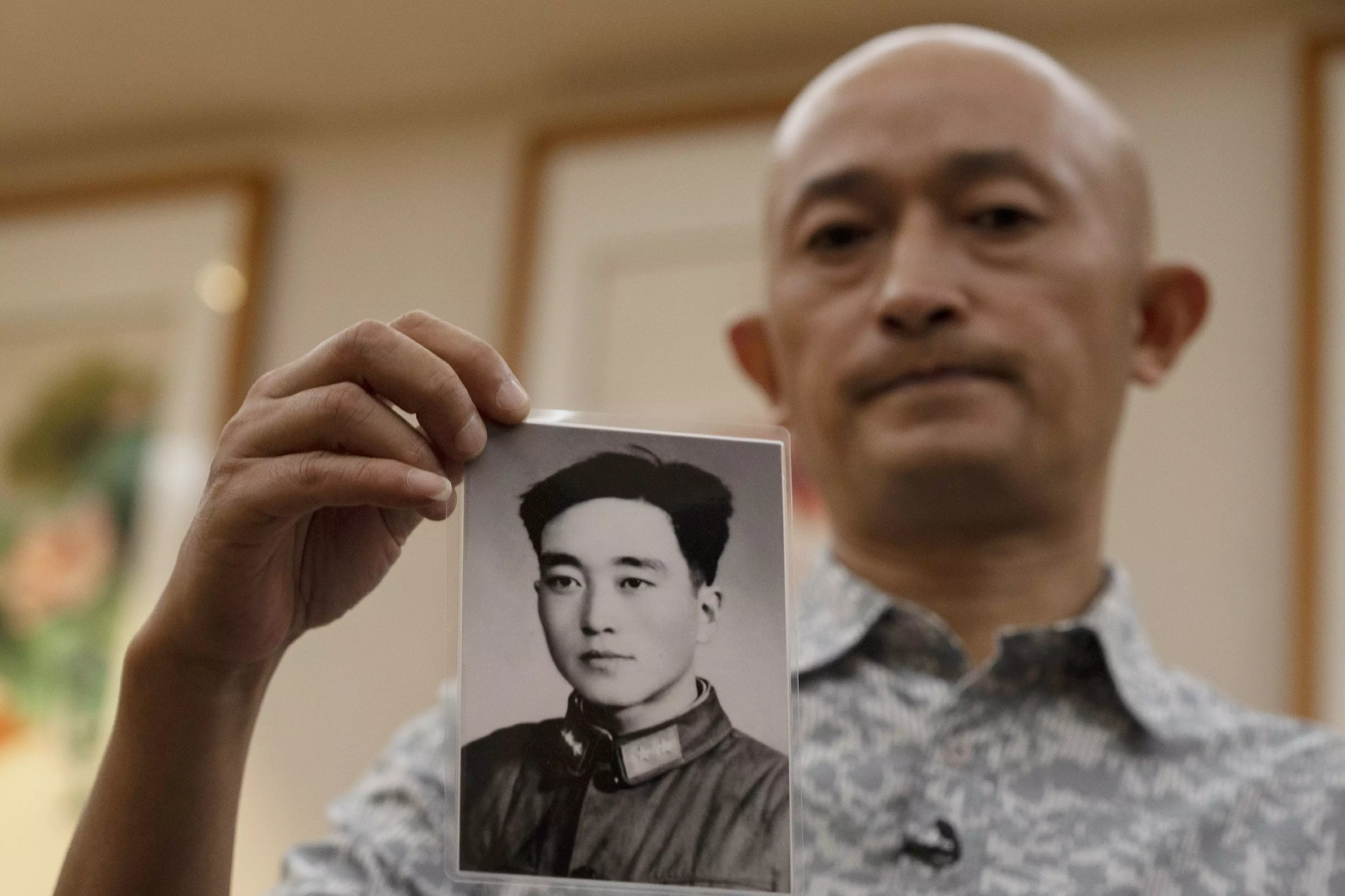 Zhang Hai lost his father to Covid-19; he's pictured holding a picture of his dad as a young man.