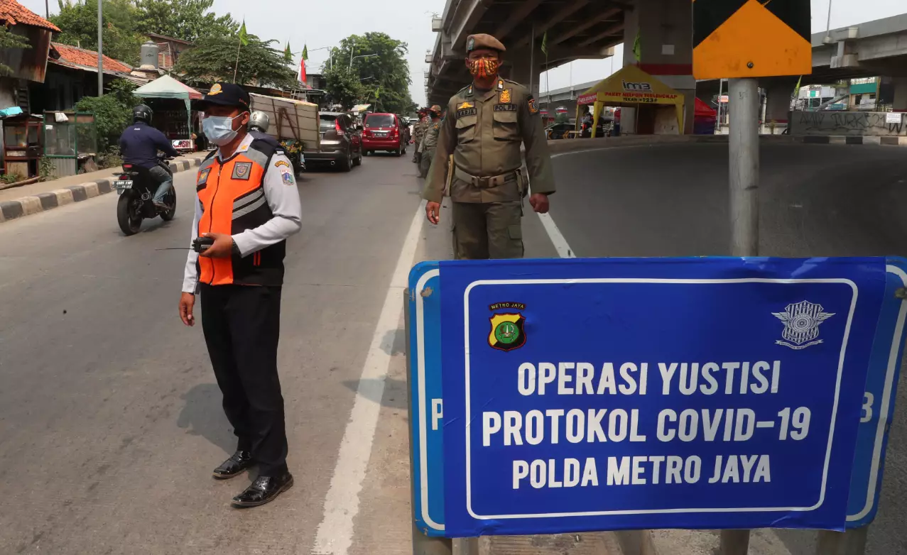 Officers stand guard at a police check point as the large-scale restriction is imposed to curb the spread of the coronavirus outbreak in Jakarta, Indonesia.