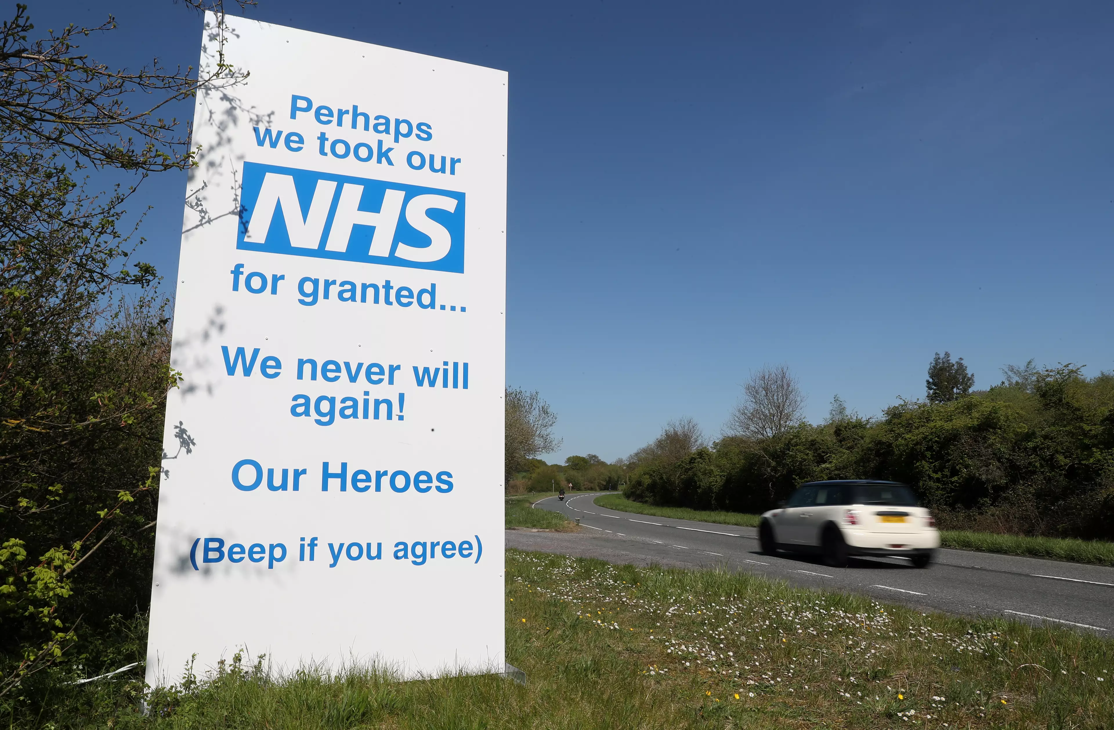 A car makes it's way past a sign in support of the NHS put up on the A30 near to Old Basing in Hampshire.