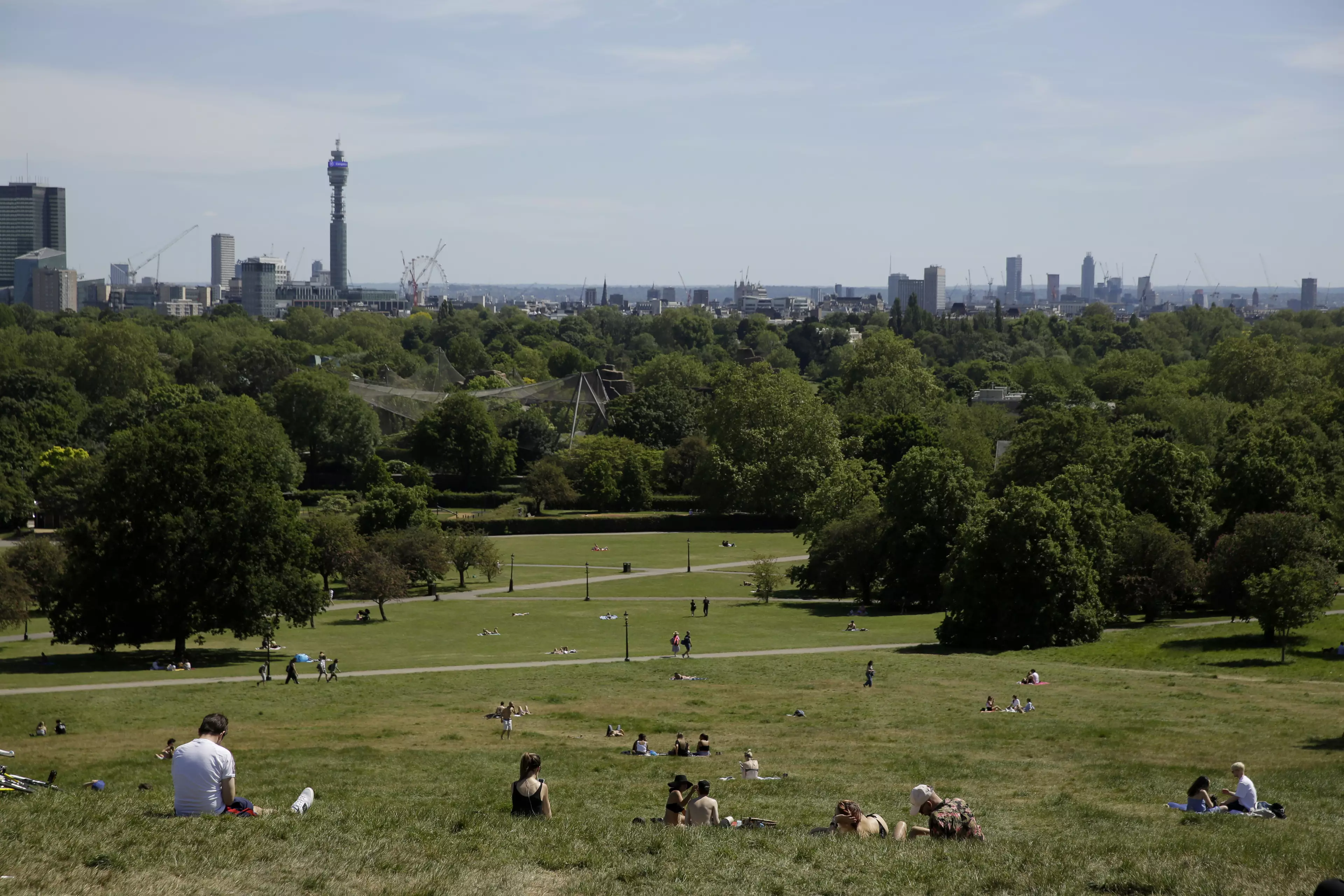 People relax during warm weather on Primrose Hill, in London.