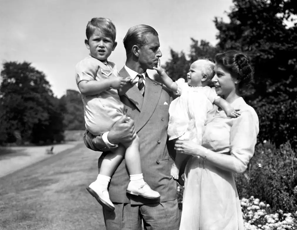Princess Anne in the arms of Princess Elizabeth, with the Duke of Edinburgh holding Prince Charles, in the grounds of Clarence House in 1951.