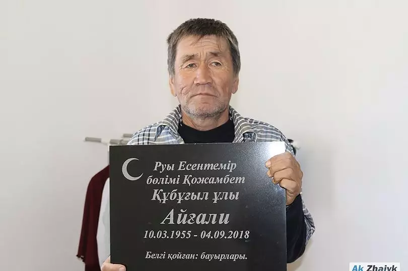 Aigali Supugaliev posed with his gravestone and doesn't he look happy to be alive?