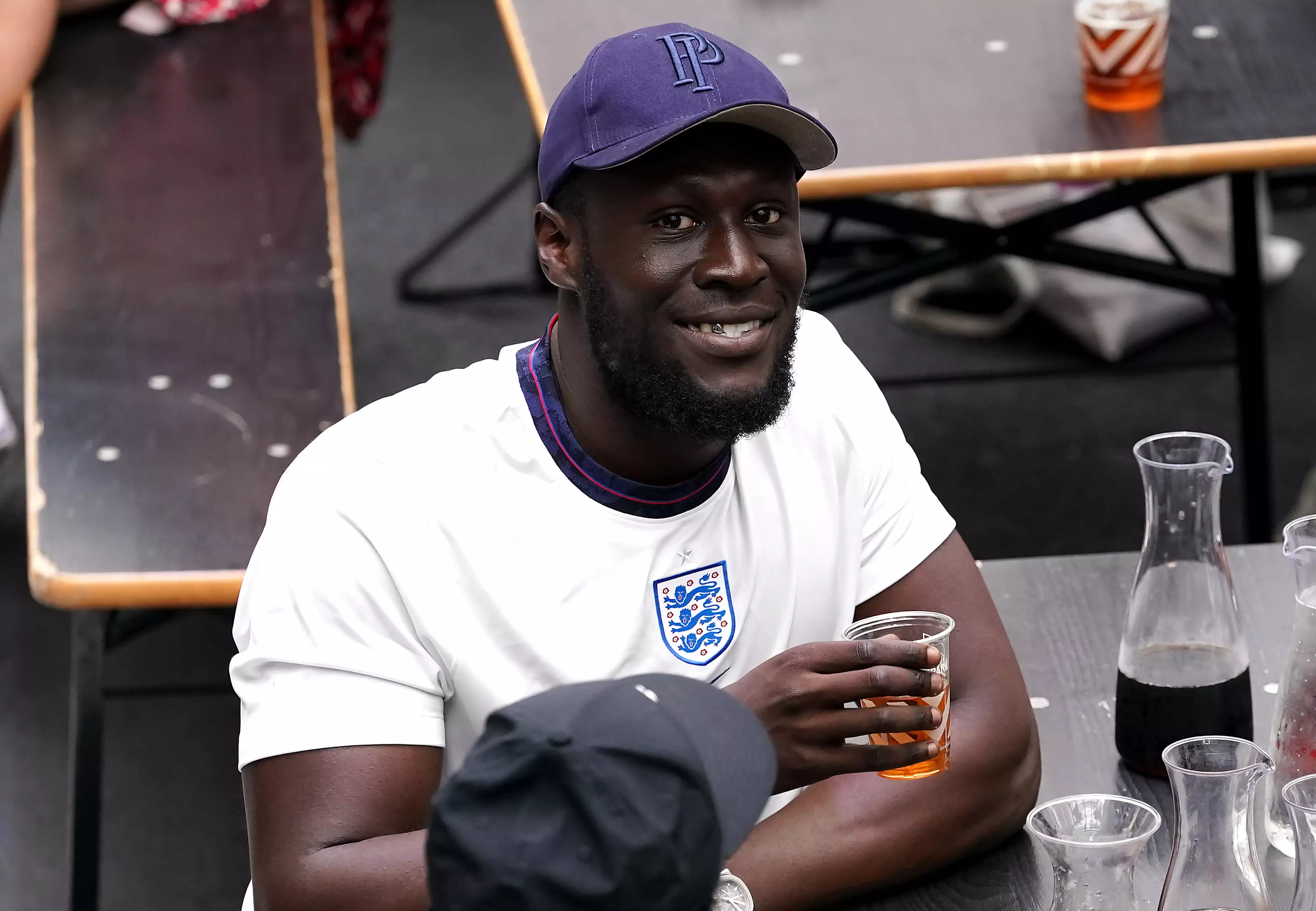 Stormzy enjoys a drink while watching the game.