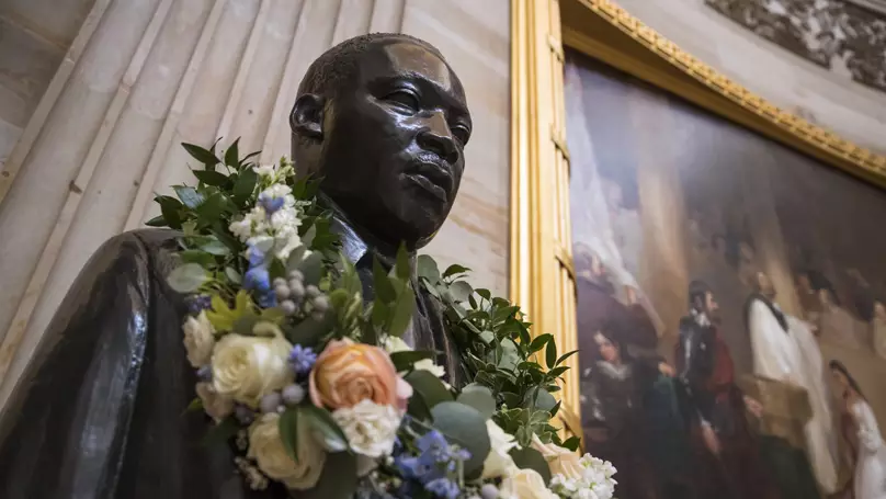 The bust of Martin Luther King Jr. is draped with a wreath of flowers to commemorate his birthday.