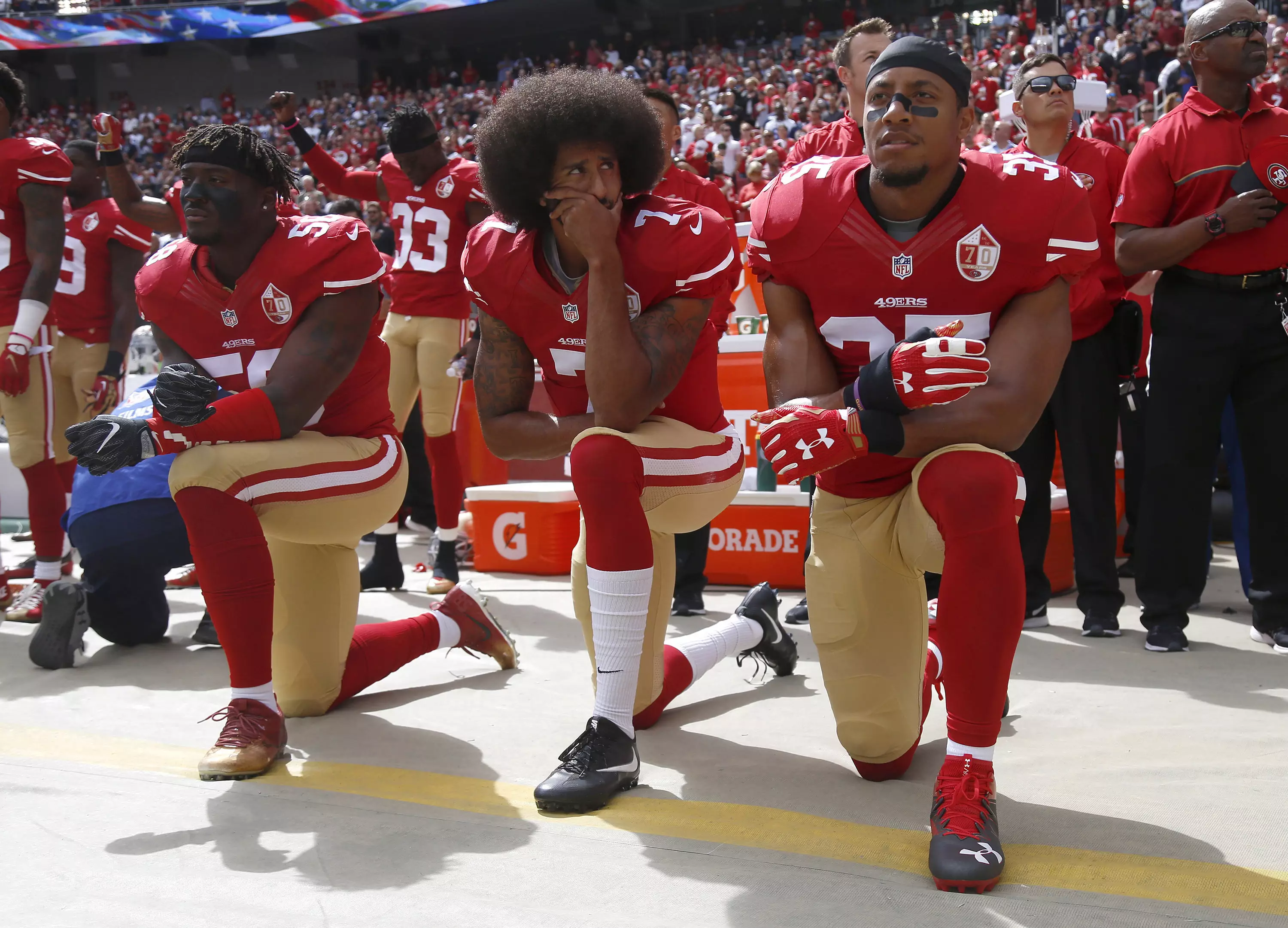 Colin Kaepernick and his teammates kneel in protest before an NFL game.