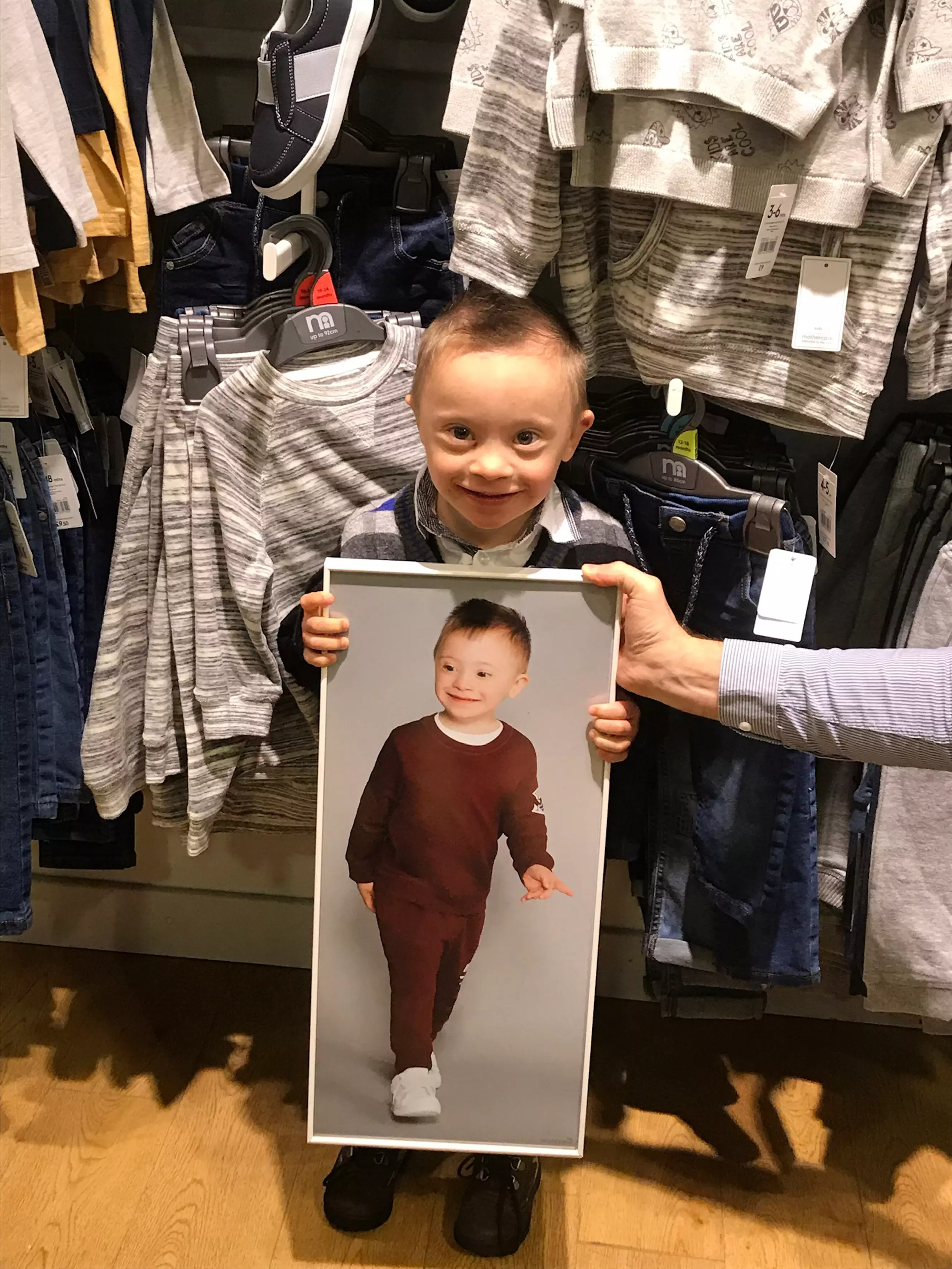 Riley proudly holding up his modelling image within a store .