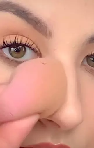 The make-up artist dabs her nose with a sponge (