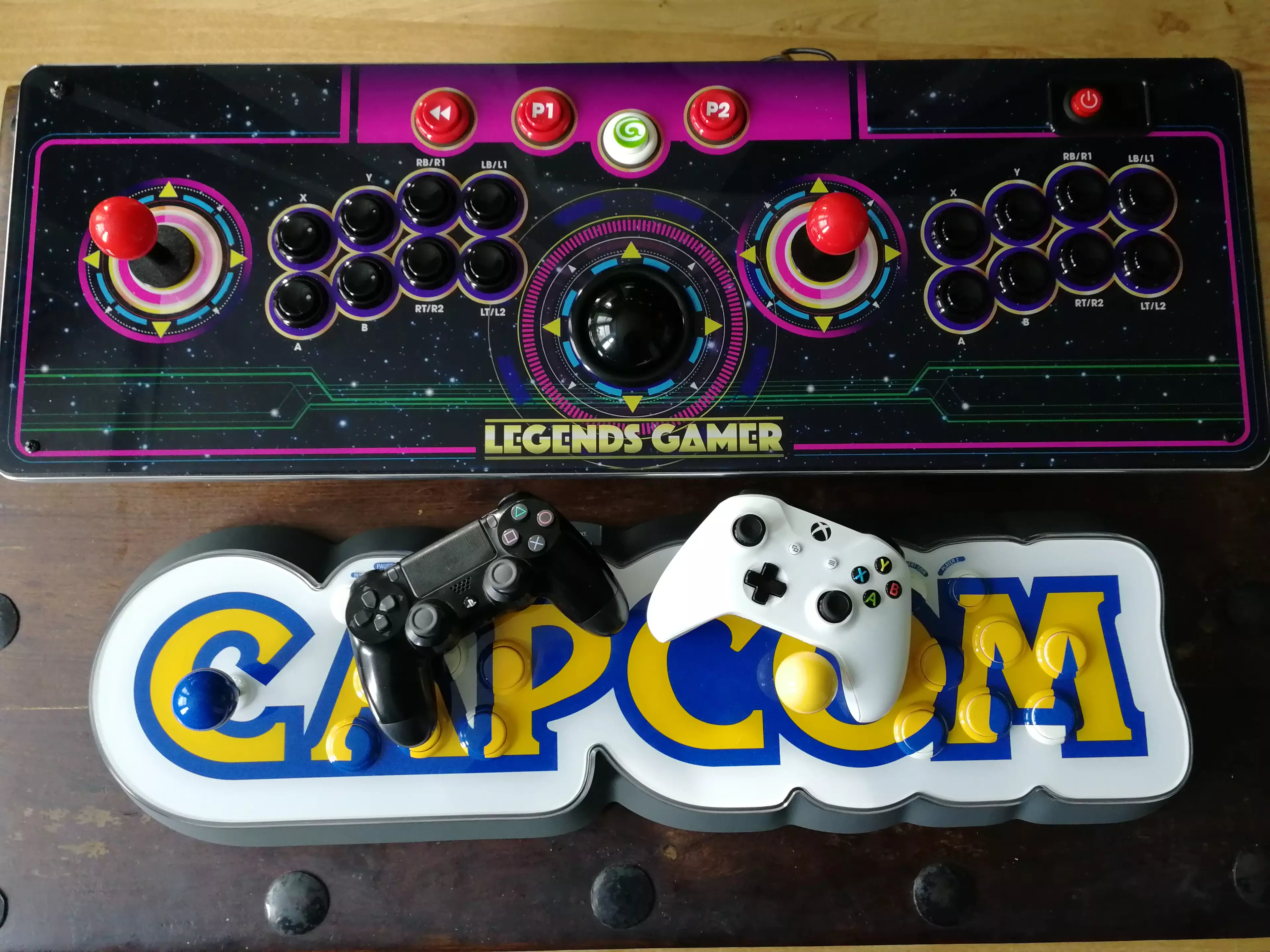 The Legends Gamer Pro next to the Capcom Home Arcade, and console controllers /