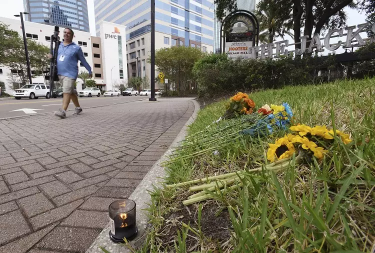 Candle and flowers left on the grass outside the site of the Jacksonville shooting.