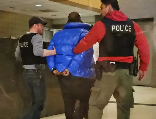 R. Kelly is escorted by police in custody at the Chicago Police Department's Central District Friday night.