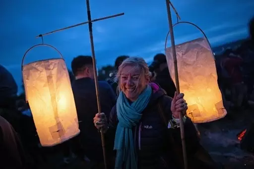 A festival-goer stands with lanterns at the stone circle during Glastonbury Festival.