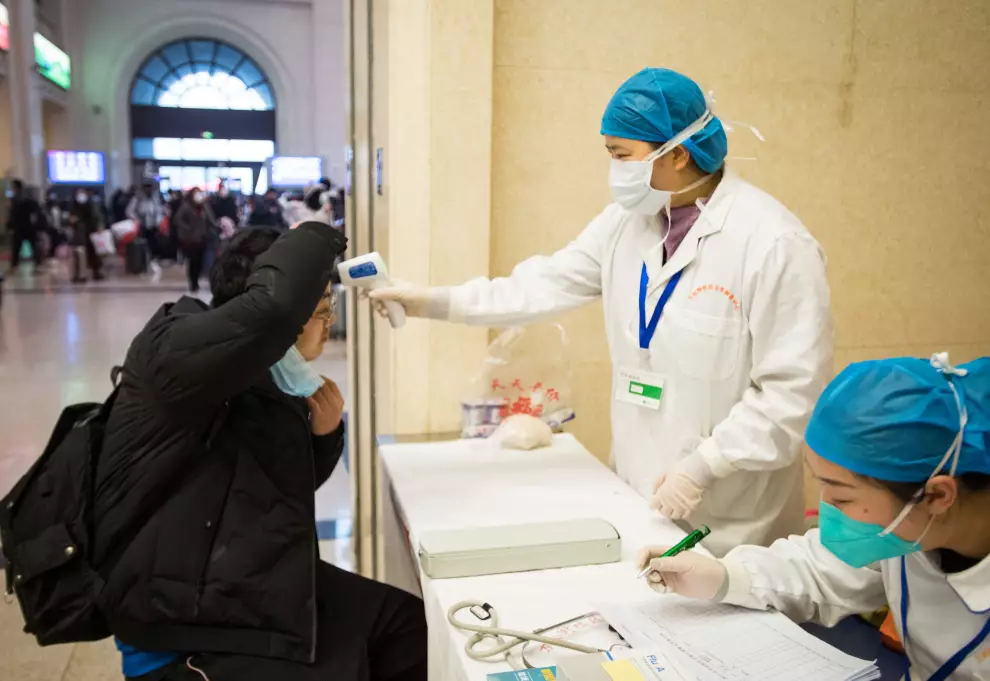 A medical worker takes a passenger's body temperature at Hankou Railway Station in Wuhan.