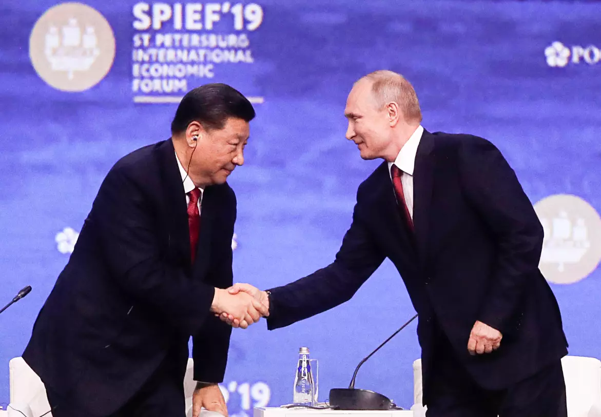 Xi and Putin shake hands.