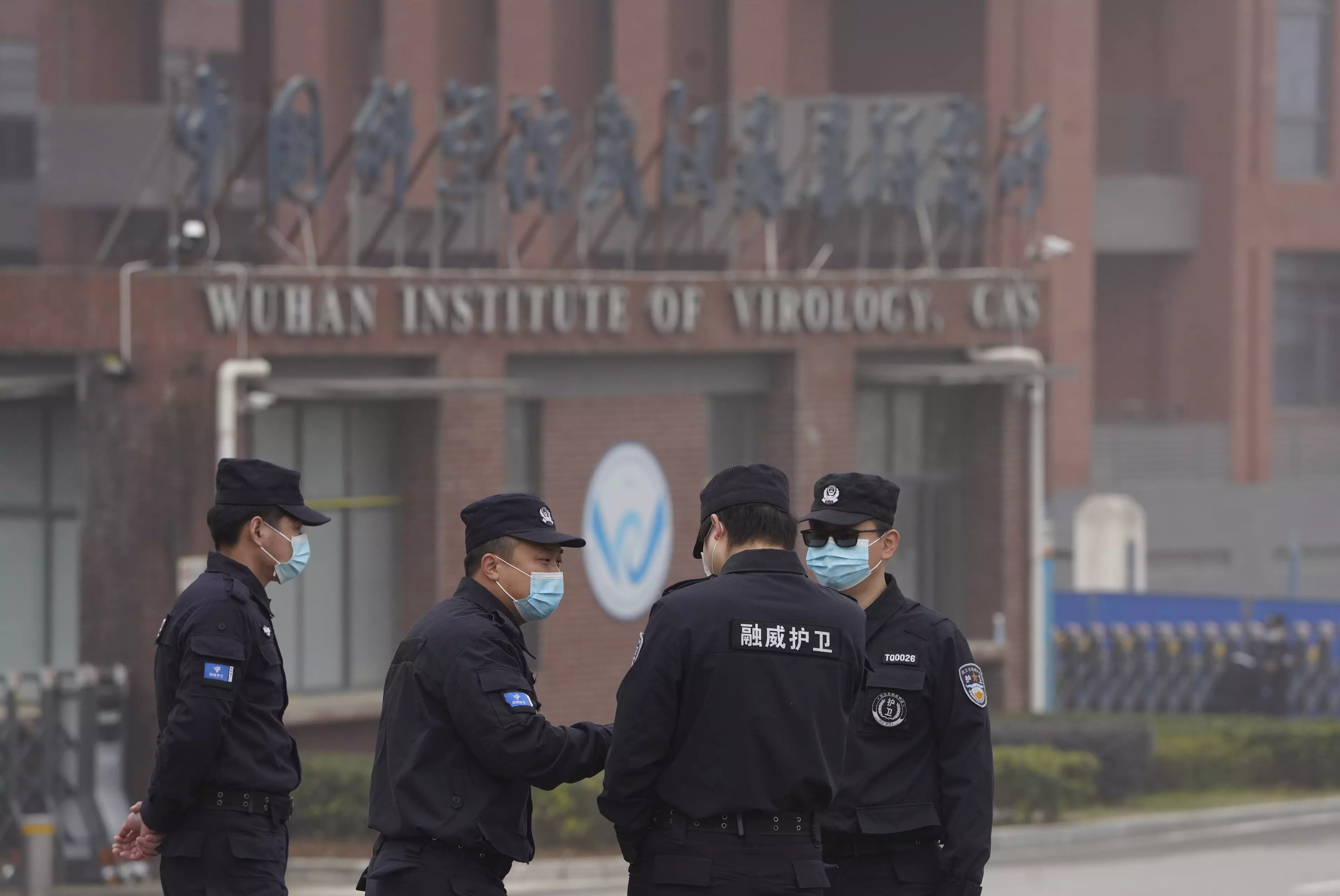 Security personnel gather near the entrance of the Wuhan Institute of Virology.