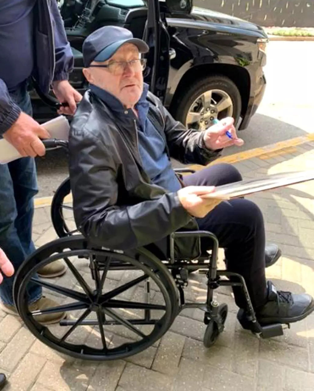 Phil Collins looks frail in a wheelchair following a fall on-stage.